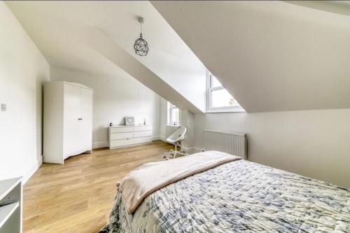 a bedroom with a bed and a chair in a attic at A beautiful newly renovated home: The Arlingford in London