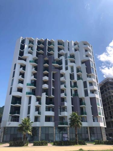 a large building with palm trees in front of it at GONIO Beachfront Cosy Apartment in Gonio