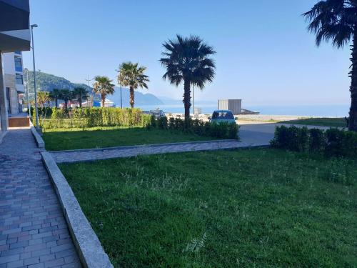 a walkway next to a lawn with palm trees at GONIO Beachfront Cosy Apartment in Gonio