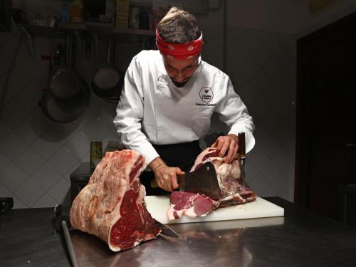 a chef cutting up a piece of meat on a cutting board at Locanda il Fienile in Naples