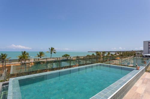 una piscina en la parte superior de un edificio con el océano en el fondo en Frente Mar Apartamento Luxuoso na praia de Cabo Branco, en João Pessoa