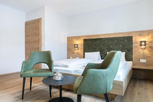オプシュタイクにあるHotel Bergland Obsteigのベッド1台と椅子2脚が備わるホテルルームです。