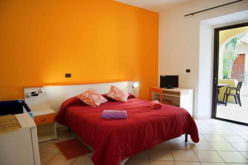 a bedroom with orange walls and a bed with a red blanket at Affittacamere Casa del Sole in Cala Gonone