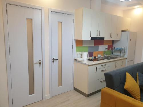 a kitchen with white cabinets and a blue couch at GONIO Beachfront Cosy Apartment in Gonio