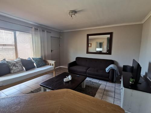 a living room with a couch and a tv at Villa De Vie Self Catering Apartment in Brackenfell