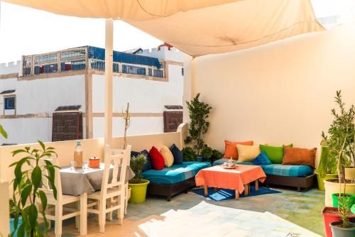 a patio with a couch and tables and an umbrella at ArtHouse Cinema Hotel in Essaouira
