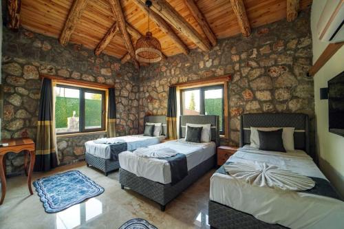 1 dormitorio con 2 camas en una habitación con paredes de piedra en Villa Diamond fethiye, en Fethiye