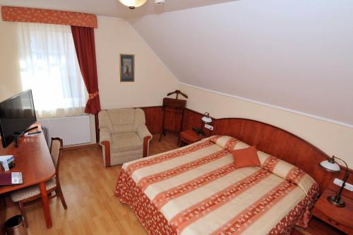 a bedroom with a bed and a desk and a television at Pátria Panzió in Eger