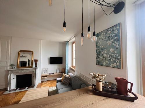 uma sala de estar com uma mesa e uma lareira em Charmant appartement plein centre ville - parking privé em Auxerre