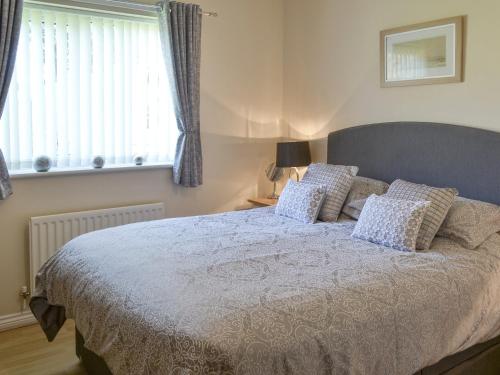 a bedroom with a bed with pillows and a window at Sandpiper in Beadnell