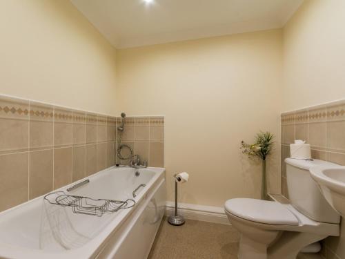 a bathroom with a tub and a toilet and a sink at 13 Great Cliff in Dawlish