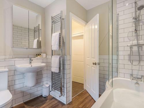 a bathroom with a sink and a toilet and a tub at Lane Ends Cottage in Disley