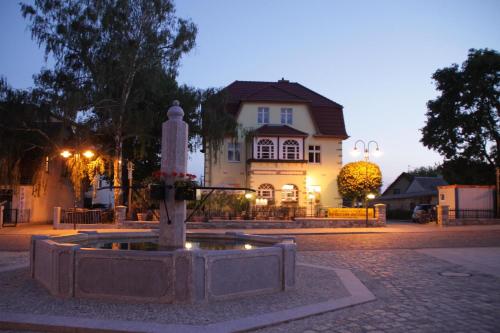 una fuente en medio de una calle frente a una casa en Chau-Asiatisches-Restaurant und Pension en Rüdersdorf