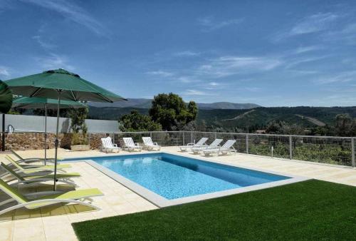 a swimming pool with chairs and an umbrella at Casa da Caneleira (Camélias de Basto) in Celorico de Basto