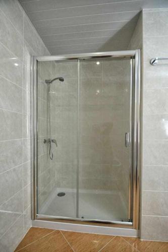a shower with a glass door in a bathroom at Casa da Caneleira (Camélias de Basto) in Celorico de Basto
