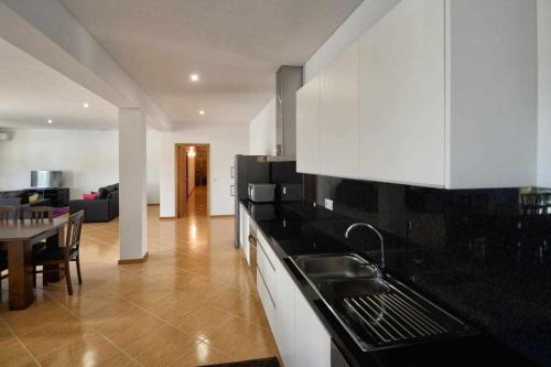 a kitchen with black counter tops and a living room at Casa da Caneleira (Camélias de Basto) in Celorico de Basto