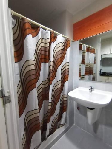 a bathroom with a sink and a shower curtain at SEA RESIDENCES Yeshua in Manila