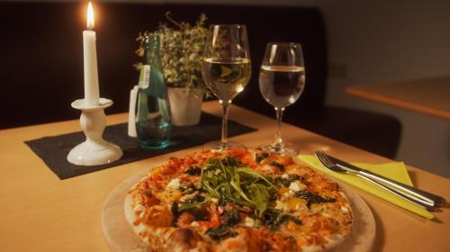 a pizza on a table with two glasses of wine at Hotel Novalis Dresden in Dresden