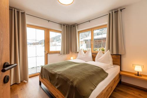 a bedroom with a large bed with two windows at Tiroli in Westendorf