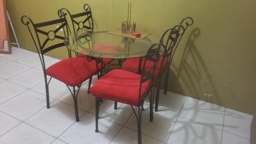 a glass table and four chairs with red seats at Pearl of the City NEW KINGSTON in Kingston