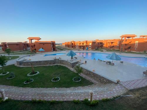 a large swimming pool with umbrellas in a resort at Chalet Amexico Paradise - Ain Sokhna in Ain Sokhna