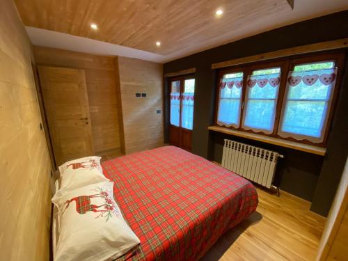 a bedroom with a bed in a room with windows at La Baita D’Nonou in SantʼAnna di Valdieri