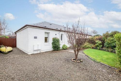 a white house with a small tree in the yard at Heather Cottage, 2 bedroom in Comrie in Comrie