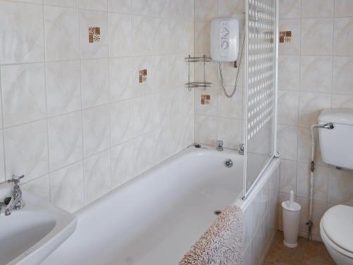 a white bathroom with a tub and a toilet at The Bridge Inn Apartment in Bridgerule