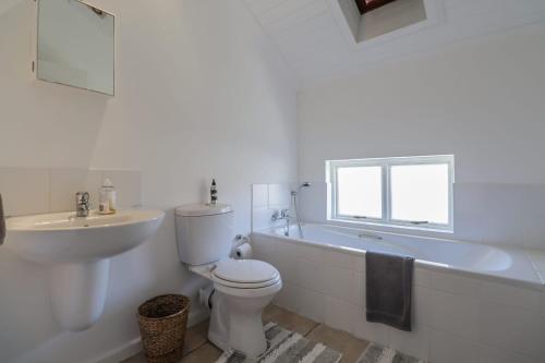 a bathroom with a white tub and a toilet and a sink at 128 @ The Dunes in Plettenberg Bay