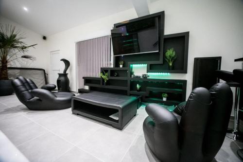 Mezza 47 spa في Précy-sur-Oise: غرفة معيشة مع كراسي جلدية سوداء وتلفزيون بشاشة مسطحة