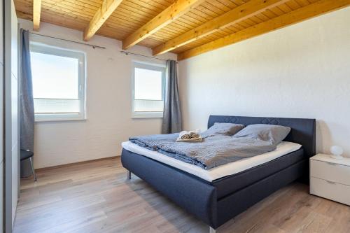 een slaapkamer met een blauw bed in een kamer met 2 ramen bij Nr 13 Robbe in Aurich