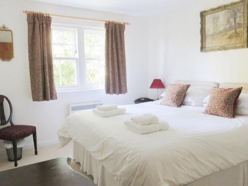 a bedroom with a white bed with towels on it at Farragon Cottage in Foss