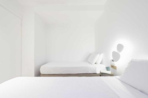 a white bedroom with two beds and a window at Cavo Delea Villas & Suites in Possidi