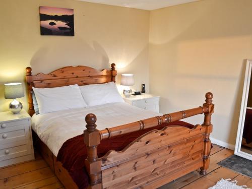 a bedroom with a large wooden bed with white sheets at Coal Miners Cottage in New Mills