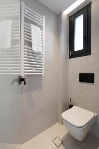 a white bathroom with a toilet and a window at Incanto Boutique Suites - Neos Kosmos in Athens
