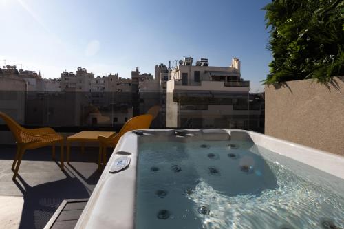 a hot tub on a balcony with a view of a city at LUX&EASY Athens Metro Suites in Athens