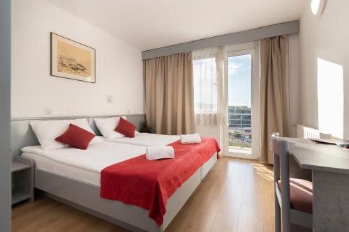 a hotel room with a bed with a red blanket at Boarding House Lucija in Kostrena