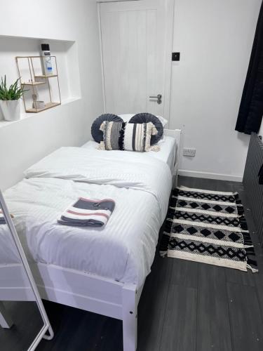 Private room and ensuite Chorlton في مانشستر: غرفة نوم بسرير ابيض وسجادة بيضاء وسوداء