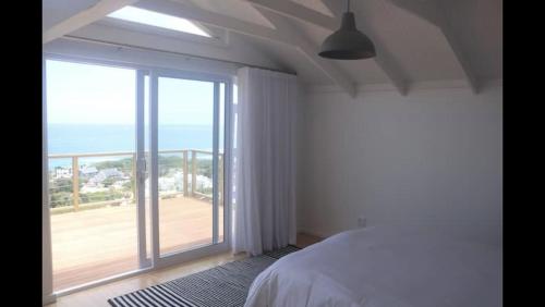 a bedroom with a bed and a large window at Brenton Ocean view in Brenton-on-Sea