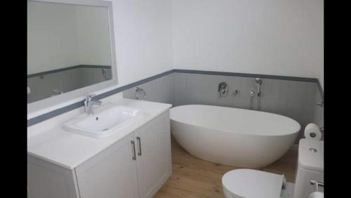 a bathroom with a tub and a sink and a toilet at Brenton Ocean view in Brenton-on-Sea