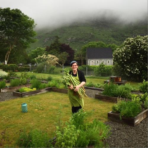a woman standing in a garden holding a plant at Gougane Barra Hotel in Ballingeary