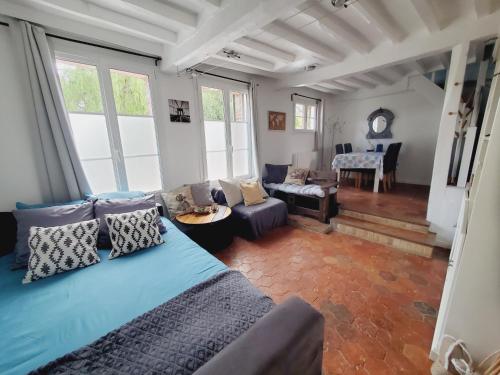 sala de estar con sofá azul y sala de estar con ventanas en Chez le Petit Peintre en Laboissière-en-Thelle