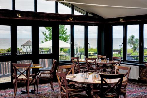 a restaurant with tables and chairs and windows at Old Hunstanton Le Strange Arms Hotel in Hunstanton