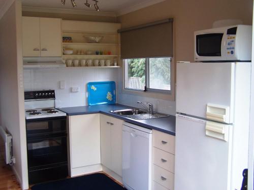 a small kitchen with a sink and a refrigerator at Pebble Shack in Coles Bay