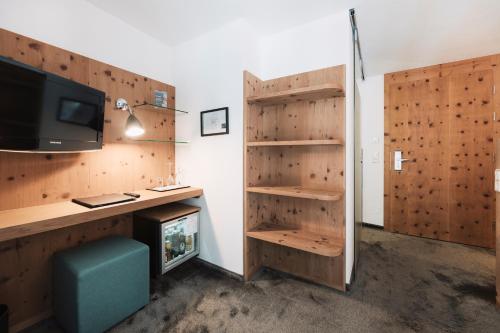 a room with a desk with a tv and a fireplace at Hotel Piz Buin in Ischgl