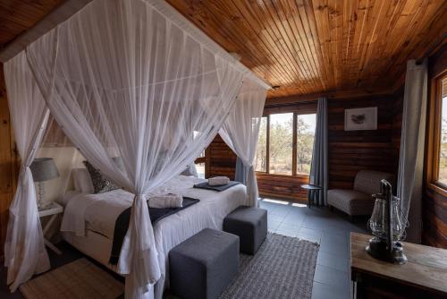a bedroom with a bed with a mosquito net at Palala River Cottages in Vaalwater