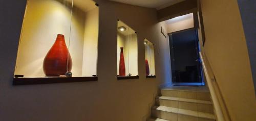 a hallway with three mirrors and a red vase on a wall at Departamento Caseros in Salta