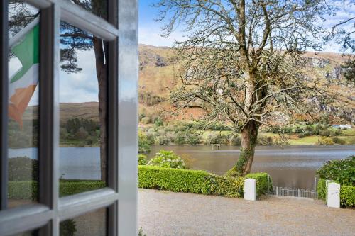 a window looking out at a lake and a tree at Gougane Barra Hotel in Ballingeary