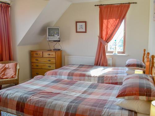 sypialnia z dwoma łóżkami i telewizorem na komodzie w obiekcie The Bungalow w mieście Gristhorpe