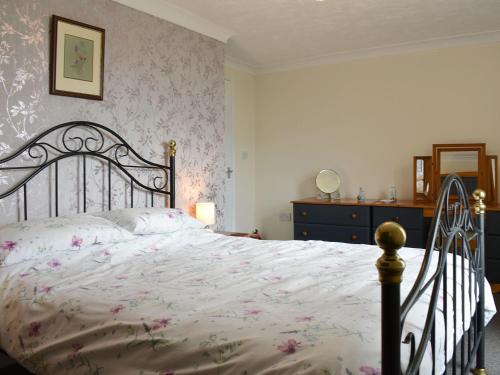 斯坦霍普的住宿－Curlew Cottage，一间卧室配有一张带粉红色花卉壁纸的大床